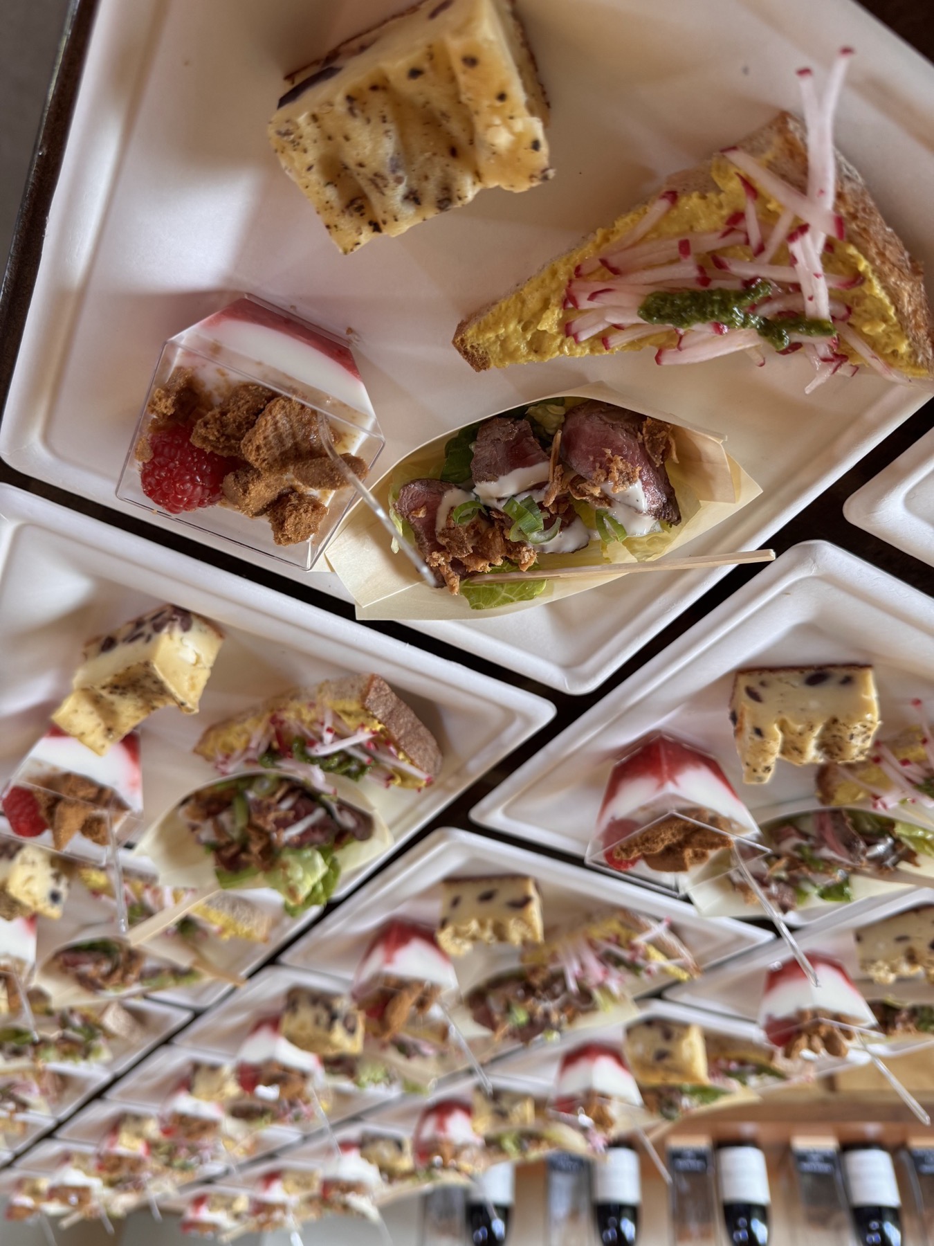 Trays of plated canapés lined up before apéritif service at a private Portland event